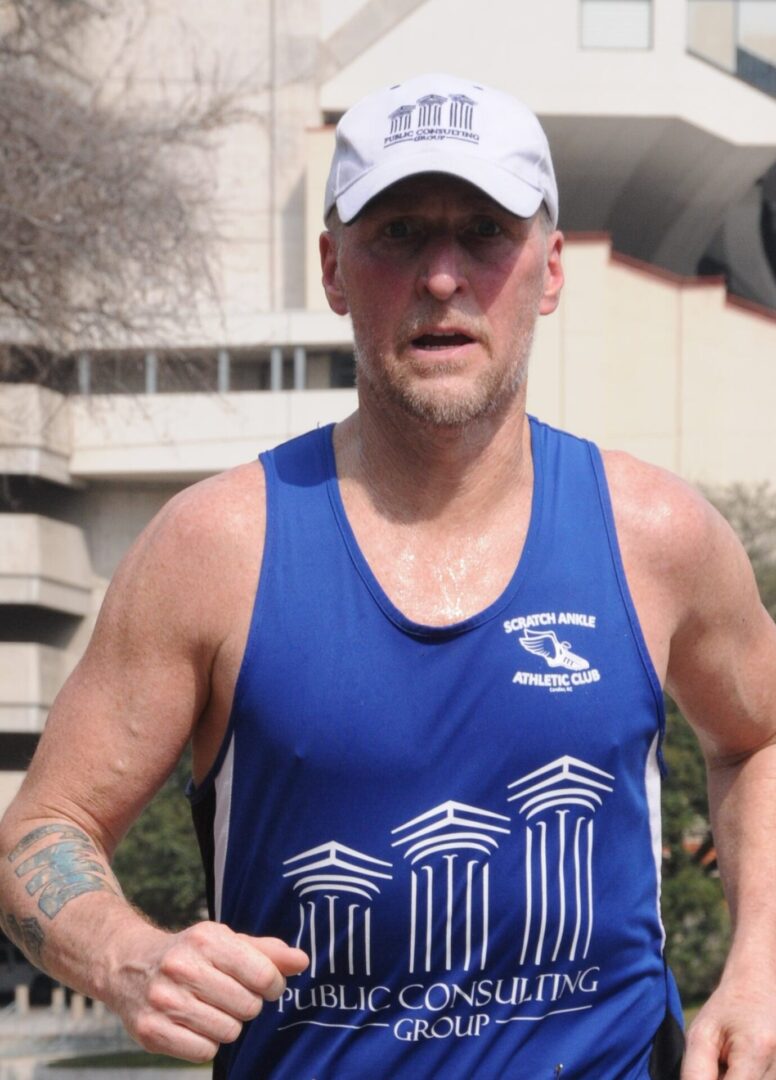 A man in blue shirt and hat running.