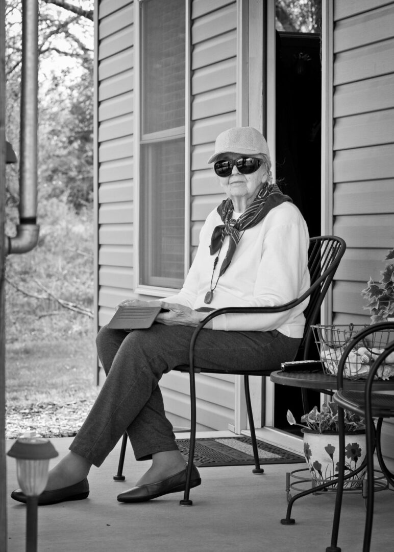 A woman sitting on the porch of her home.