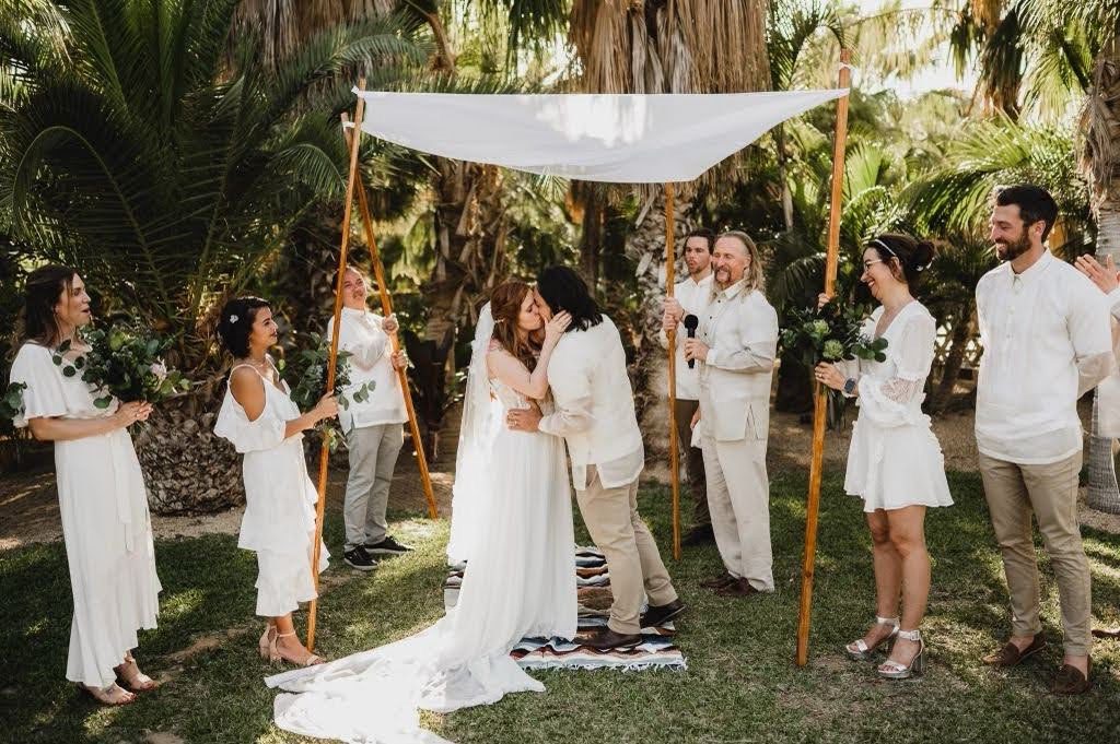 A couple kissing under an umbrella at their wedding.