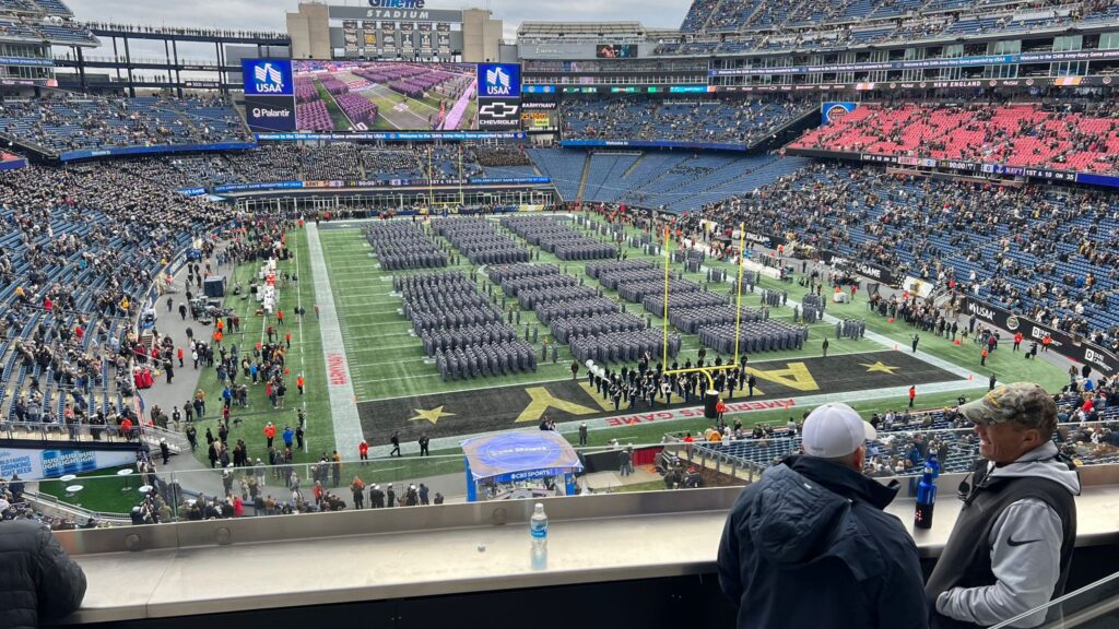 A crowd of people watching an army band perform.